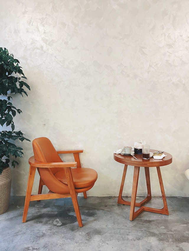 A orange chair beside a brown coffee table with an indoor plant behind it
