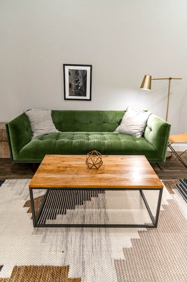 A green sofa provides a pop of color in a living room with neytral colors
