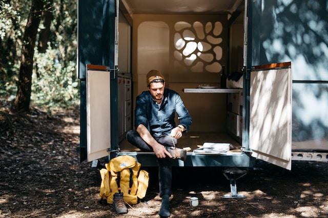 Man sitting outside his tiny house while tying his shoes
