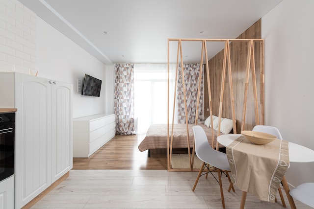 A wooden room divider separates the bedroom from the dining room