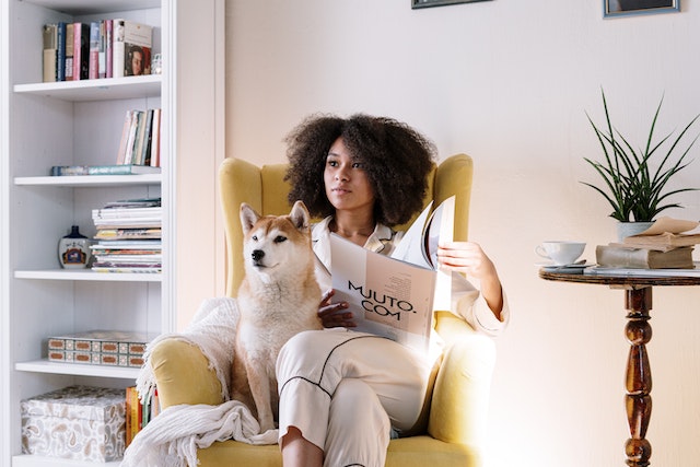 Woman sitting on a yellow couch with her pet dog