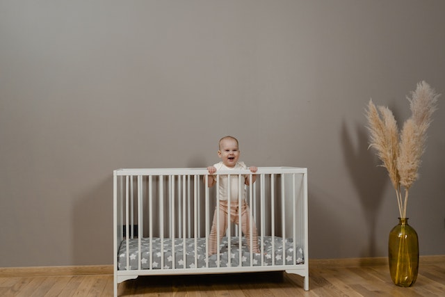 A child's crib set up in a room with a gray wall