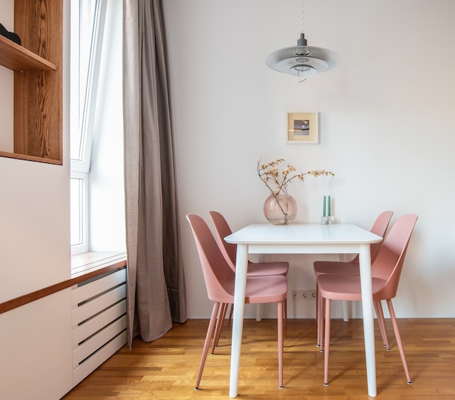 A minimalist dining room setup of white table and soft pink chairs